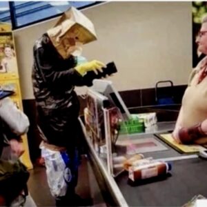 hombre pagando en un supermercado en la pandemia con una bolsa de papel en la cabeza a modo de mascarilla